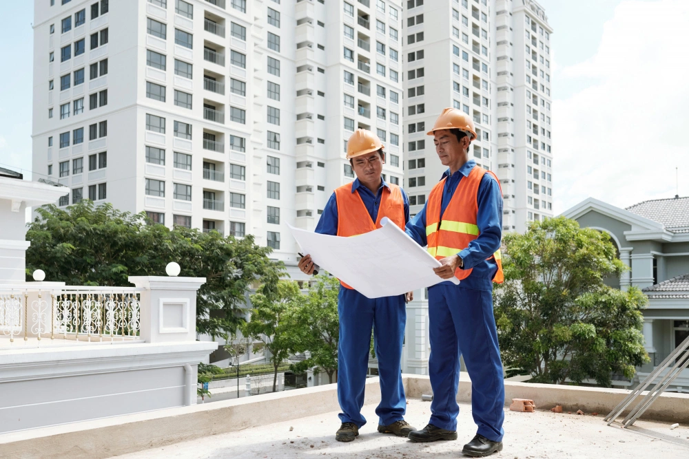 Construction workers discussing plans at building site with tools and blueprints, showing digital marketing for construction companies